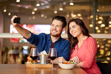 Image showing couple taking selfie by smartphone at restaurant