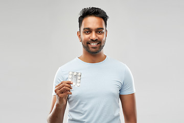 Image showing smiling indian man with pills over grey background