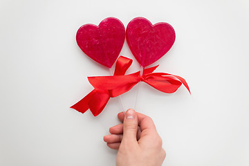 Image showing close up of hand holding red heart shaped lollipop