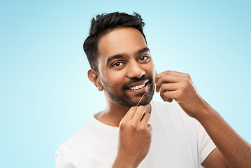 Image showing indian man with dental floss cleaning teeth