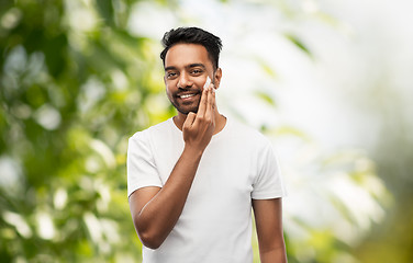 Image showing happy indian man applying cream to face