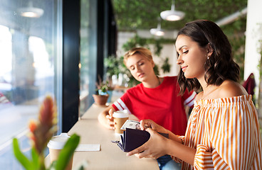 Image showing female friends paying for coffee at cafe