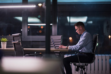 Image showing man working on laptop in dark office