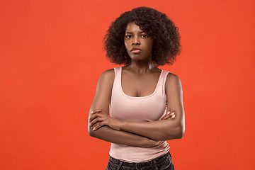 Image showing The serious business woman standing and looking at camera against red background.