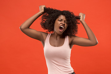 Image showing The young emotional angry woman screaming on red studio background