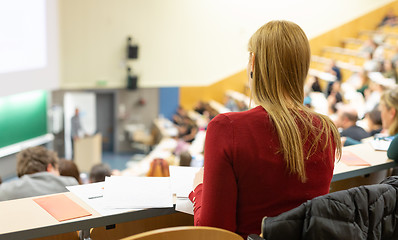 Image showing Female student attending faculty lecture workshop making notes.