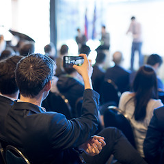 Image showing Businessman takes a picture of corporate business presentation at conference hall using smartphone.
