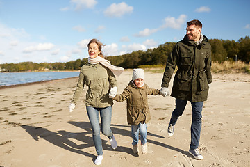 Image showing happy family running along autumn beach