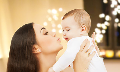 Image showing mother kissing baby over christmas lights