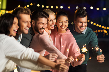 Image showing happy friends with sparklers at rooftop party