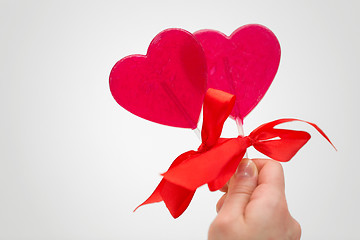 Image showing close up of hand holding red heart shaped lollipop