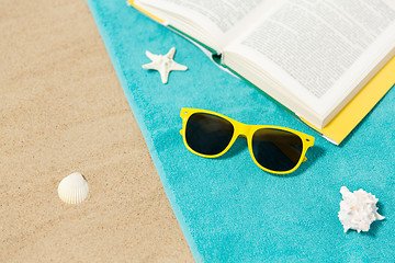 Image showing sunglasses and book on beach towel on sand