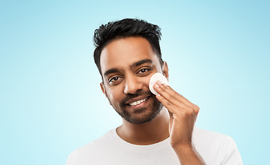 Image showing smiling indian man cleaning face with cotton pad