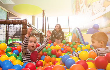 Image showing young mom playing with kids in pool with colorful balls