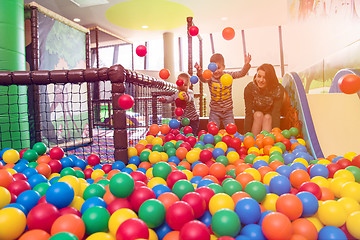 Image showing young mom playing with kids in pool with colorful balls