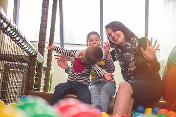 Image showing young mom playing with kids in pool with colorful balls