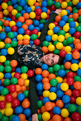 Image showing young mom playing with kids in pool with colorful balls