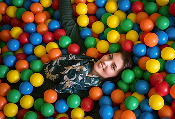 Image showing young mom playing with kids in pool with colorful balls