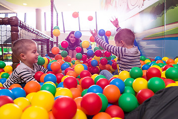 Image showing young mom playing with kids in pool with colorful balls