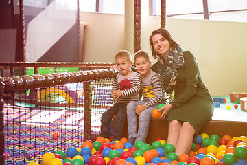 Image showing young mom playing with kids in pool with colorful balls