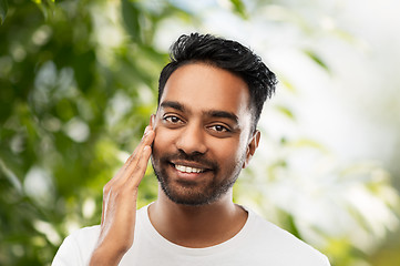 Image showing smiling indian man touching his face