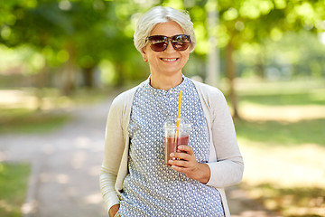 Image showing senior woman drinking takeaway shake at park