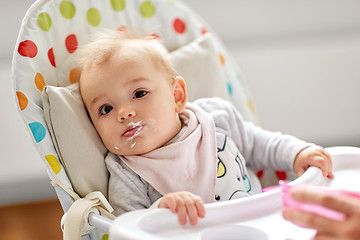 Image showing little baby girl eating in highchair at home