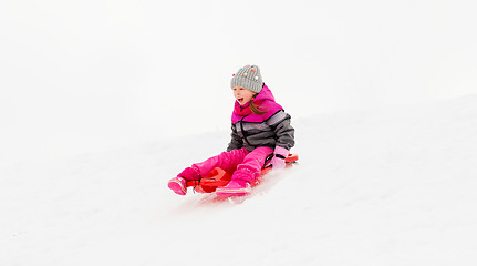 Image showing happy little girl sliding down on sled in winter