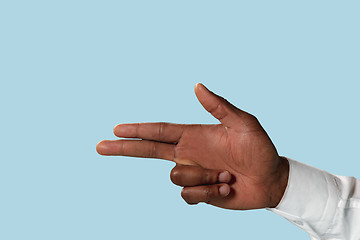 Image showing Male hand demonstrating a gesture of gun isolated on blue background