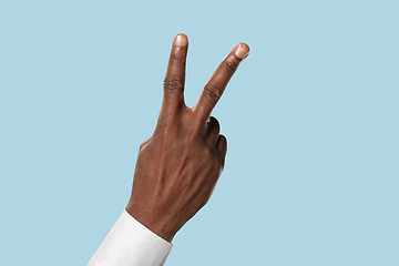 Image showing Male hand demonstrating a gesture of peace isolated on blue background