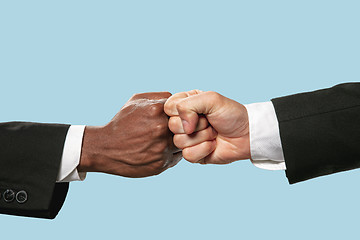 Image showing Two male hands competion in arm wrestling isolated on blue studio background