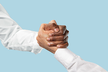 Image showing Two male hands competion in arm wrestling isolated on blue studio background