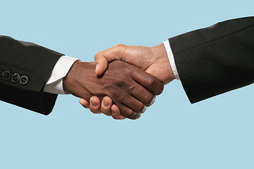 Image showing Two male hands shaking isolated on blue studio background