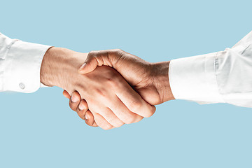 Image showing Two male hands shaking isolated on blue studio background