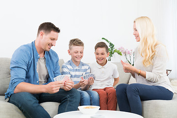 Image showing Happy young family playing card game at home.