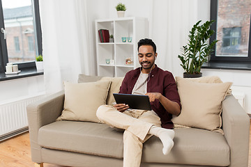 Image showing man in earphones with tablet pc listening to music