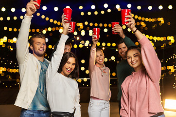 Image showing friends toasting party cups on rooftop at night