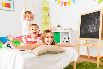 Image showing happy little kids having fun in bed at home
