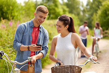 Image showing couple with smartphone and bicycles in summer