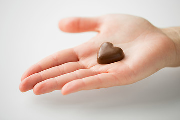 Image showing close up of hand with heart shaped chocolate candy