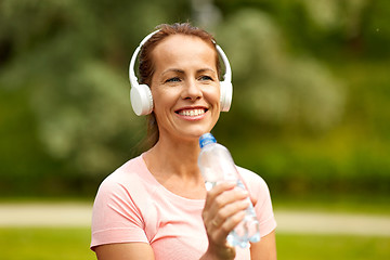 Image showing woman in headphones with bottle of water at park
