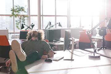 Image showing businessman sitting with legs on desk