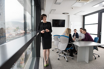 Image showing Elegant Woman Using Mobile Phone by window in office building