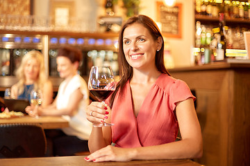 Image showing happy woman drinking red wine at bar or restaurant