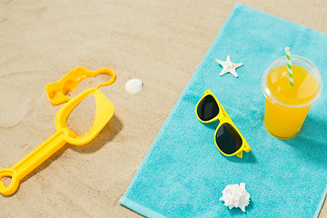 Image showing sunglasses, sand toys and juice on beach towel