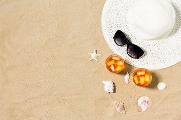 Image showing cocktails, sun hat and sunglasses on beach sand