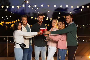 Image showing friends clinking party cups on rooftop at night