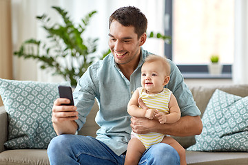 Image showing father with baby daughter using smartphone at home