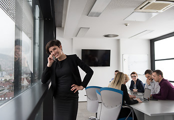 Image showing Elegant Woman Using Mobile Phone by window in office building