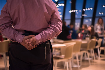 Image showing waiter standing with hands behind his back